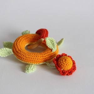 Bijtring, rammelspeeltje in de kleuren warm geel, donker oranje en groen of rood, roze en groen.